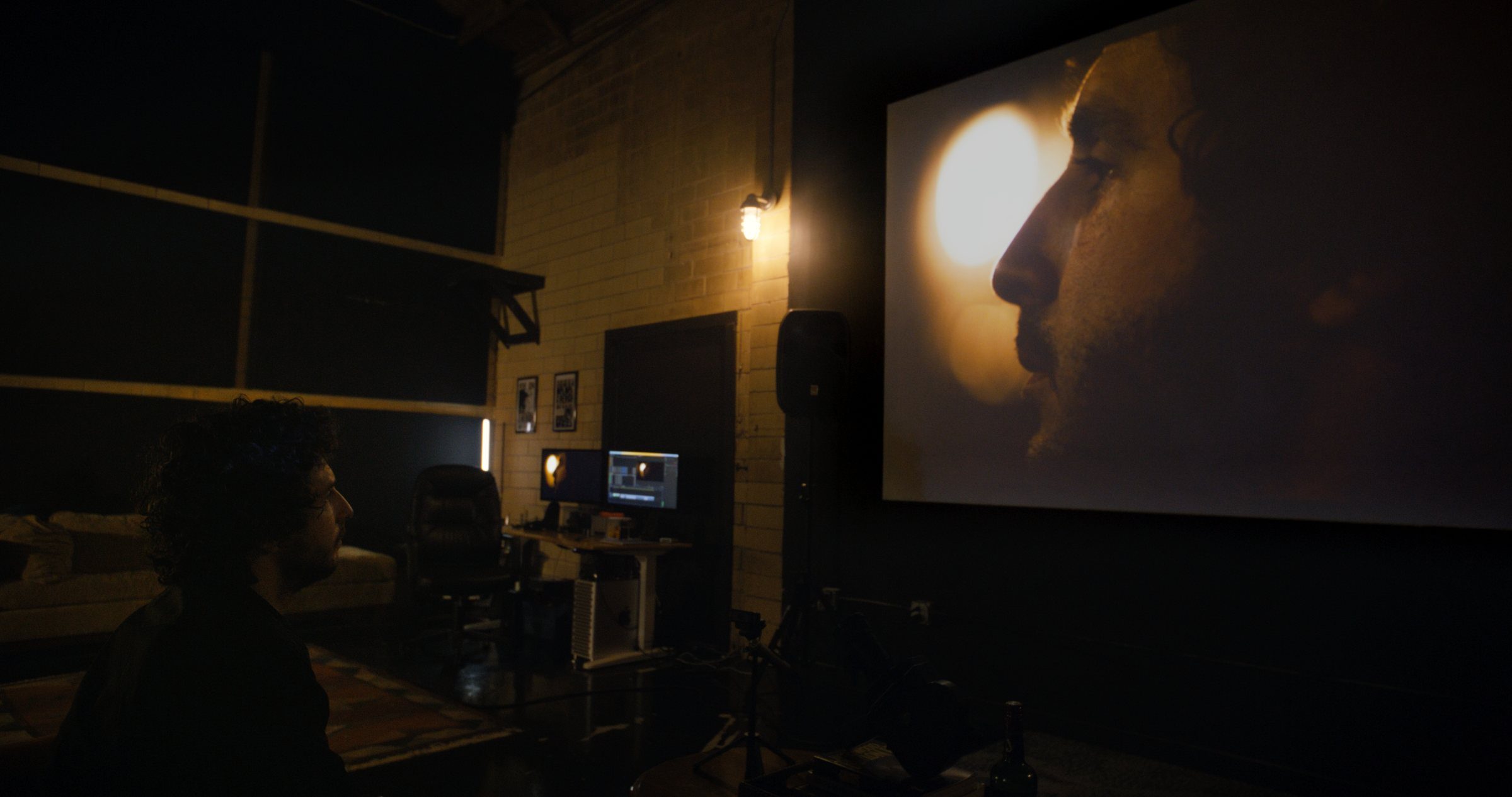 Still from AUTOFICTION: Nick Paul White's profile projected on a screen in a dark room